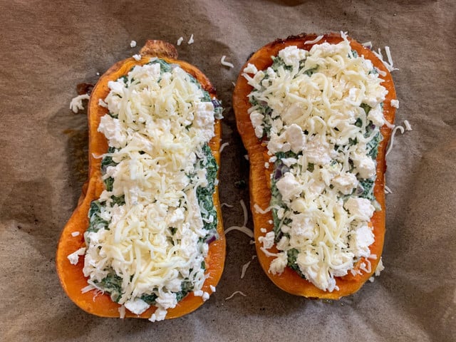Fülle ordentlich Spinat und Käse in die Kürbishälften.