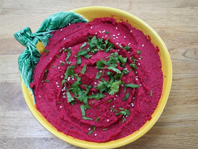 Der Rote-Bete-Hummus sieht besonders appetitlich aus, wenn du ihn mit frischen Kräutern garnierst. 