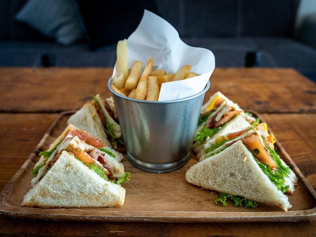 Zum Club-Sandwich werden klassischerweise Kartoffelchips oder Pommes serviert.